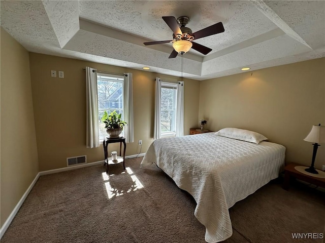 carpeted bedroom featuring visible vents, baseboards, a ceiling fan, a textured ceiling, and a tray ceiling