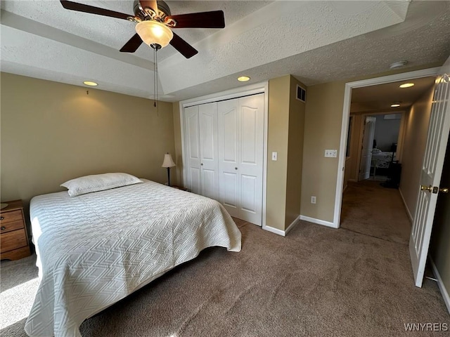 carpeted bedroom featuring baseboards, a closet, a textured ceiling, visible vents, and ceiling fan