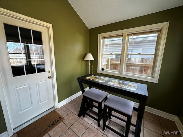 tiled dining room featuring baseboards and lofted ceiling