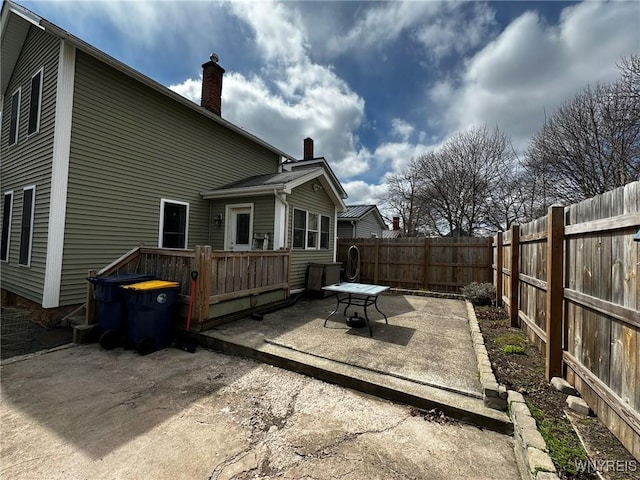 rear view of property with a patio area, a fenced backyard, and a chimney