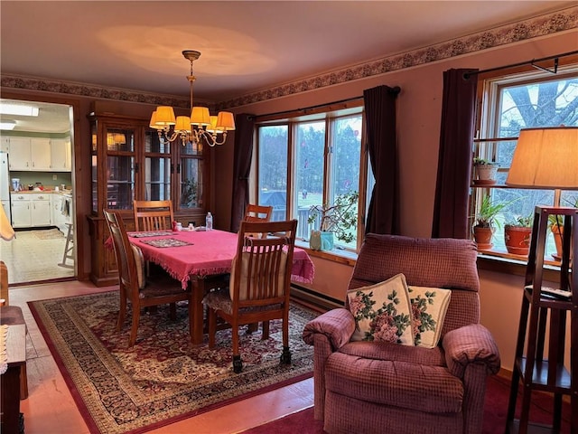 dining area with a wealth of natural light, an inviting chandelier, and wood finished floors