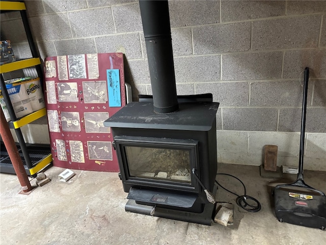 details with a wood stove, unfinished concrete flooring, and concrete block wall