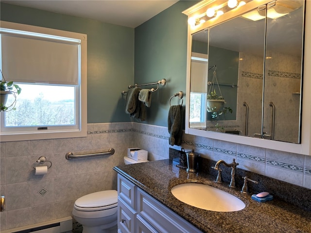 bathroom with a tile shower, vanity, toilet, tile walls, and a baseboard radiator