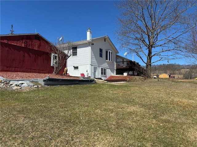 exterior space featuring a chimney, stairs, a deck, and a lawn