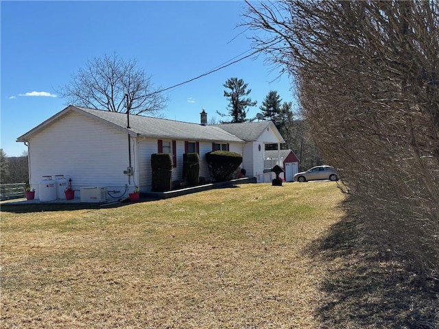 view of side of home featuring a garage, a chimney, and a lawn