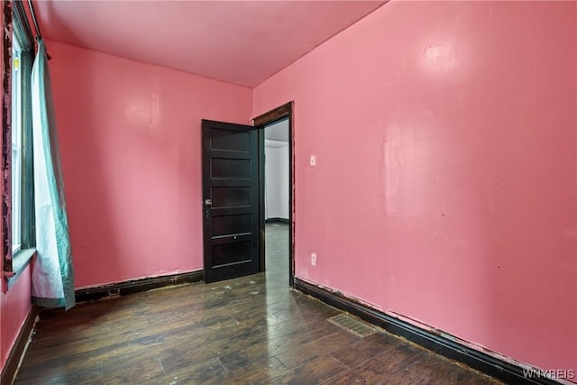 spare room featuring visible vents, baseboards, and dark wood-style floors