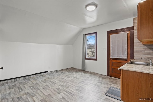 additional living space featuring light wood-style floors, a sink, and vaulted ceiling