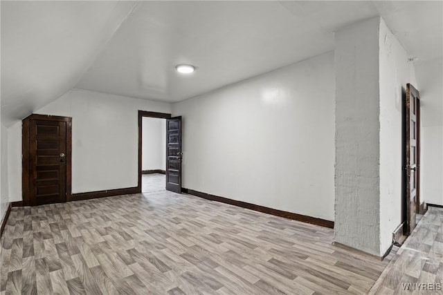 additional living space with light wood-type flooring, baseboards, and lofted ceiling