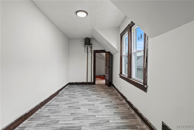 additional living space featuring light wood-style flooring, vaulted ceiling, and baseboards