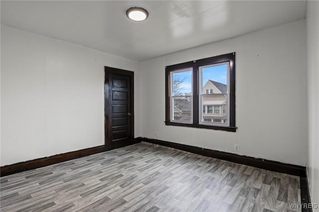 unfurnished room with baseboards and light wood-type flooring