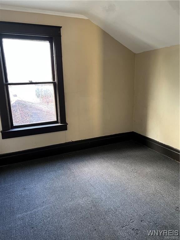 additional living space with baseboards and vaulted ceiling