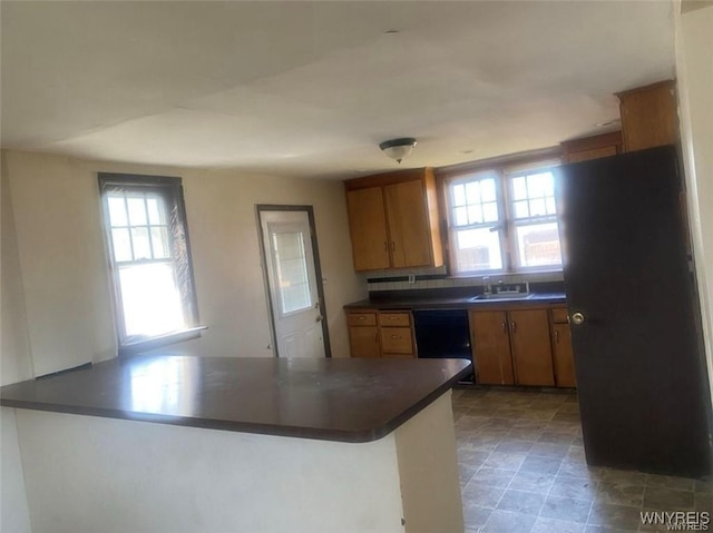 2405 Michigan Ave, Niagara Falls, NY 14305 - kitchen featuring a peninsula, dark countertops, black appliances, brown cabinetry, and a sink