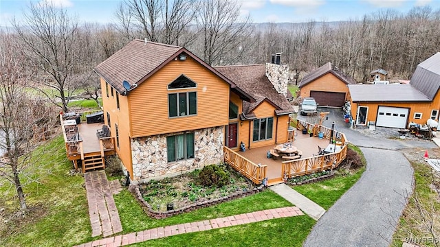view of front of property featuring a chimney, a front yard, a wooden deck, a garage, and stone siding