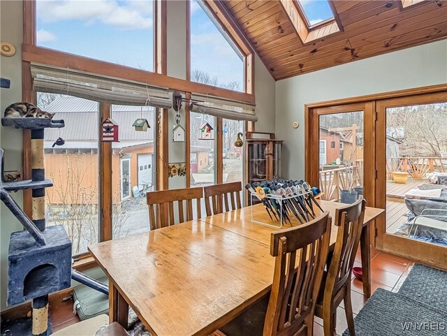 tiled dining area featuring a wood stove, high vaulted ceiling, and a skylight