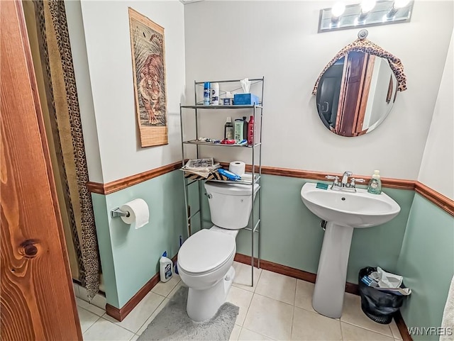bathroom featuring toilet, baseboards, a sink, and tile patterned flooring