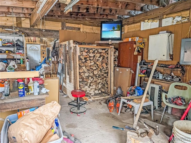 miscellaneous room with concrete flooring, wood walls, and electric panel