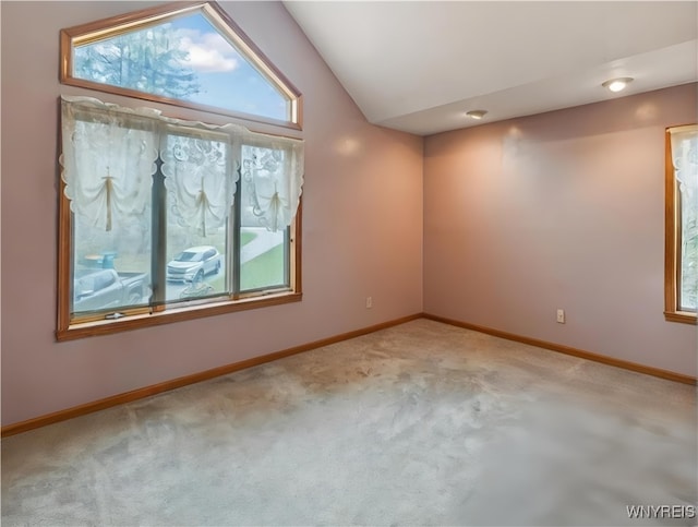 carpeted empty room with baseboards and lofted ceiling