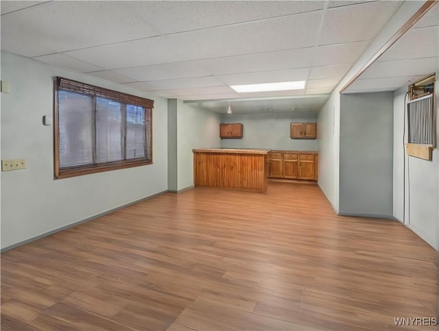 bar featuring baseboards, a drop ceiling, and light wood finished floors