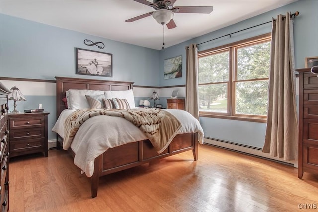bedroom with a baseboard heating unit, light wood-style floors, and ceiling fan