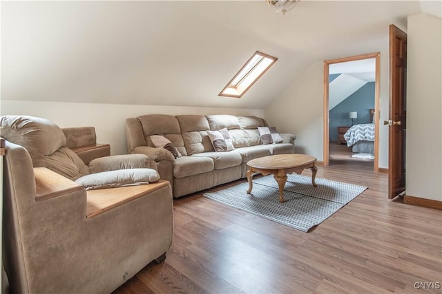 living area featuring vaulted ceiling with skylight, wood finished floors, and baseboards