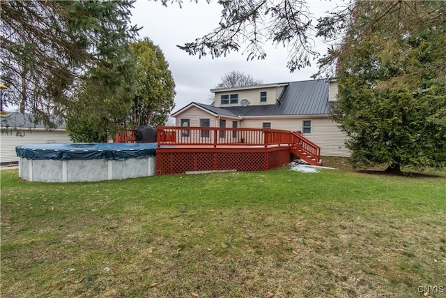 rear view of property featuring a deck, a covered pool, and a yard