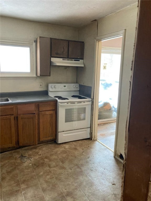 5125 Deliverance Ave, Williamson, NY 14505 - kitchen featuring a sink, dark countertops, electric stove, under cabinet range hood, and brown cabinetry