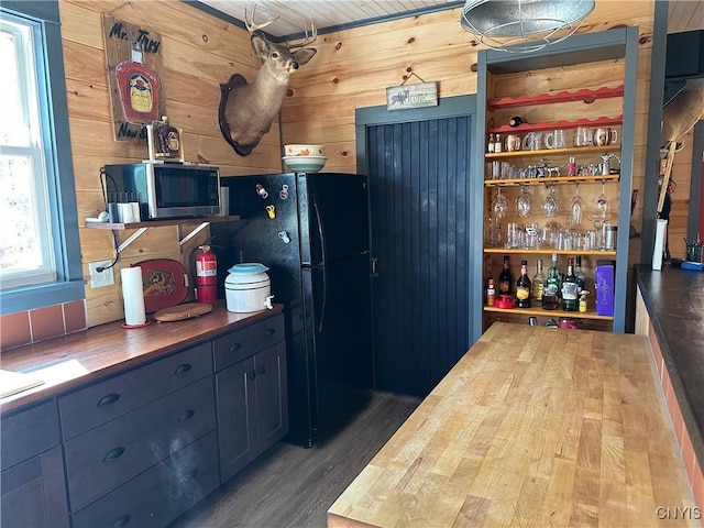 kitchen featuring freestanding refrigerator, stainless steel microwave, wood counters, wood finished floors, and wood walls
