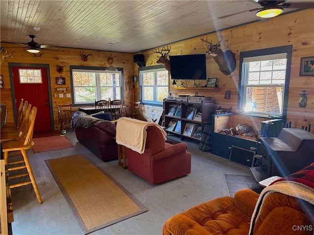 living area featuring hardwood / wood-style floors, wooden walls, and ceiling fan