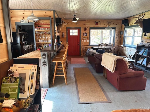 living area with wood walls, ceiling fan, hardwood / wood-style floors, and a healthy amount of sunlight