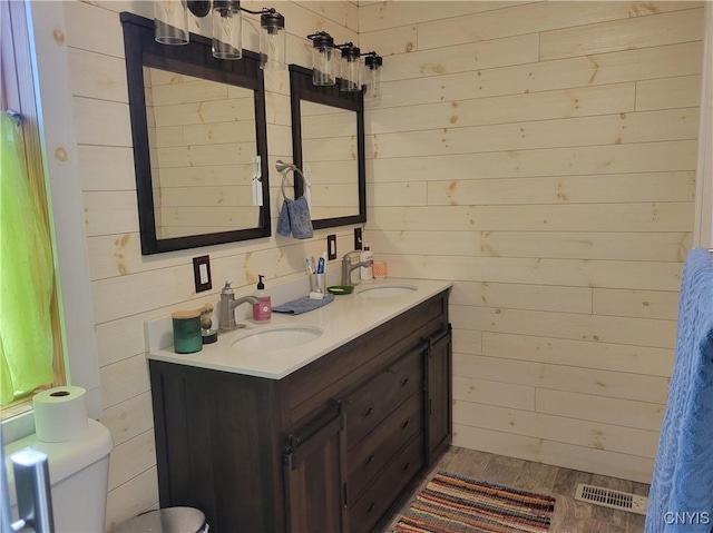 165 Howe St, Le Ray, NY 13612 - bathroom featuring wood walls, double vanity, toilet, and wood finished floors