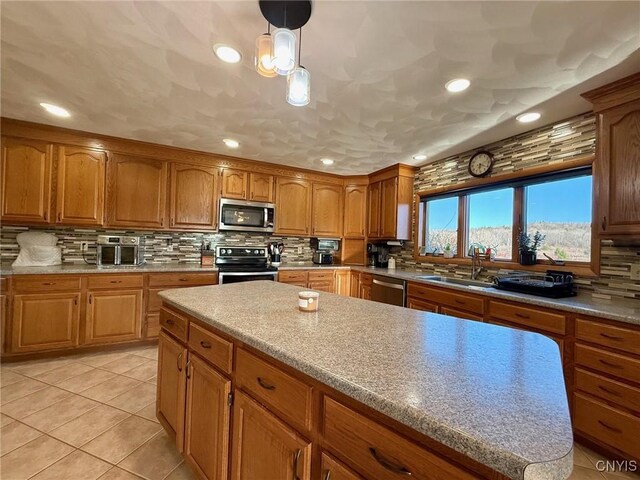 kitchen featuring tasteful backsplash, light tile patterned flooring, a sink, stainless steel appliances, and brown cabinets