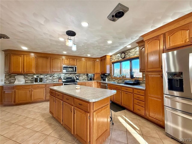 kitchen featuring a center island, a sink, appliances with stainless steel finishes, brown cabinetry, and backsplash