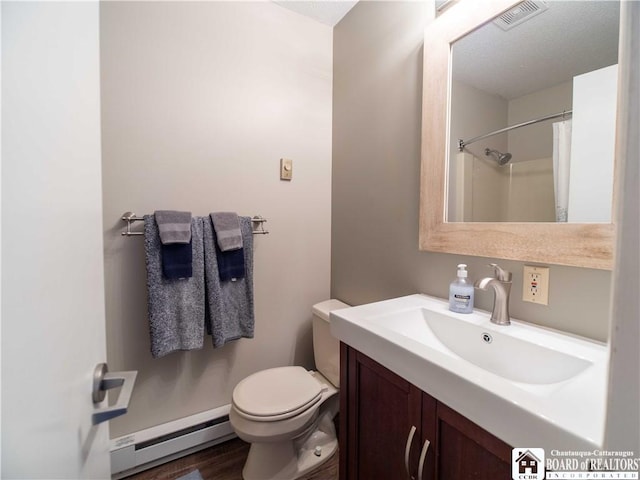 bathroom featuring visible vents, toilet, baseboard heating, vanity, and wood finished floors