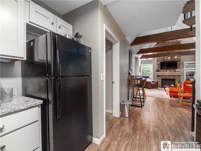 kitchen featuring baseboards, a fireplace, white cabinetry, freestanding refrigerator, and wood finished floors