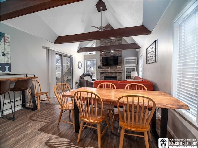 dining area featuring lofted ceiling with beams, a fireplace, a wall unit AC, ceiling fan, and wood finished floors