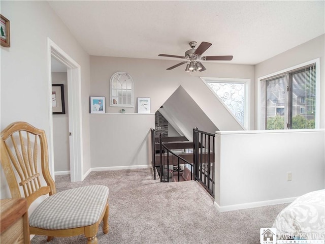 sitting room featuring carpet flooring, an upstairs landing, baseboards, and ceiling fan