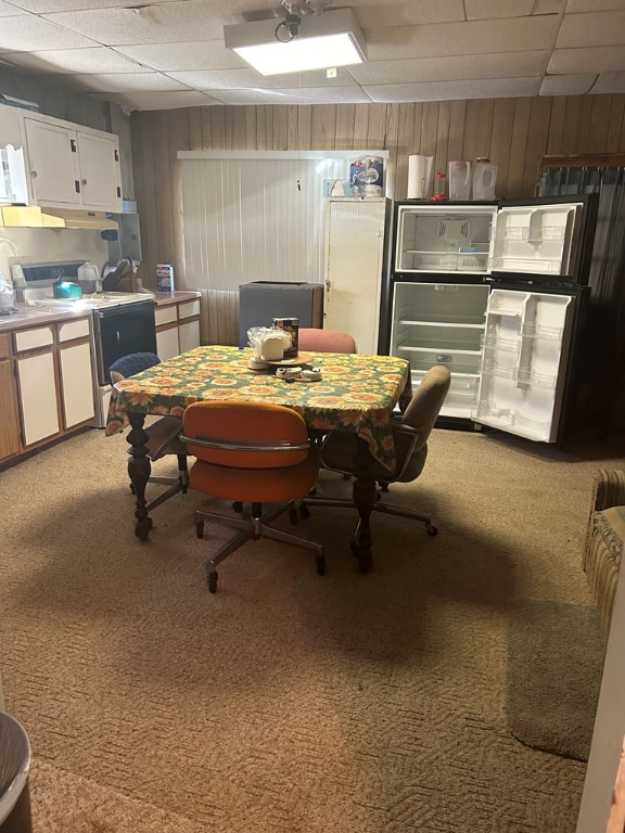 dining area featuring wooden walls and light carpet