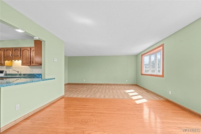 unfurnished living room featuring light wood-style flooring and baseboards