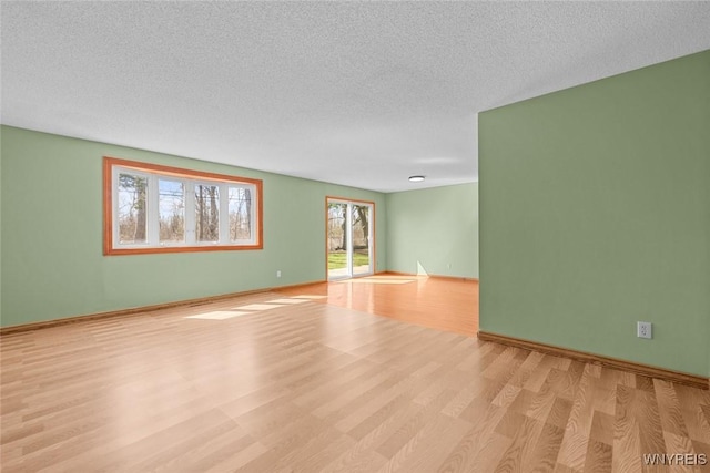 spare room with light wood-style flooring, baseboards, and a textured ceiling