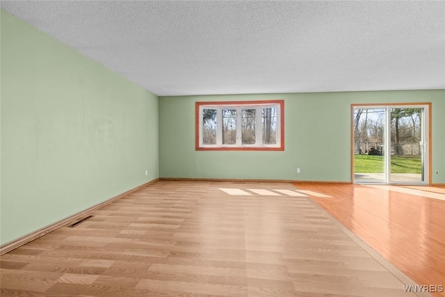 unfurnished living room featuring visible vents, baseboards, wood finished floors, and a textured ceiling