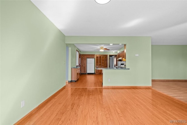 unfurnished living room featuring light wood-style flooring, baseboards, and a ceiling fan