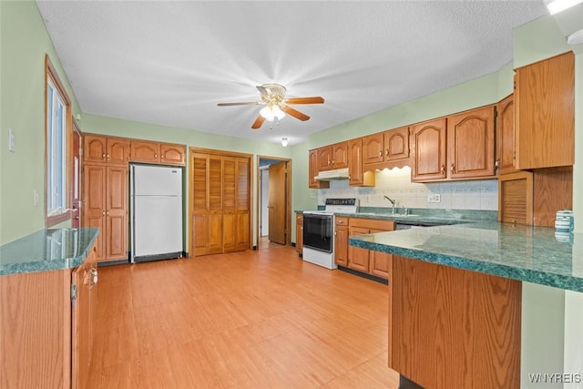 kitchen featuring brown cabinets, tasteful backsplash, white appliances, and ceiling fan