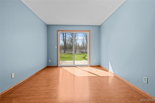unfurnished room featuring a textured ceiling, baseboards, and wood finished floors
