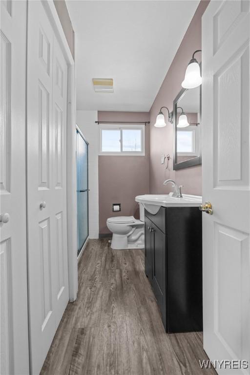full bath featuring toilet, a shower stall, vanity, and wood finished floors