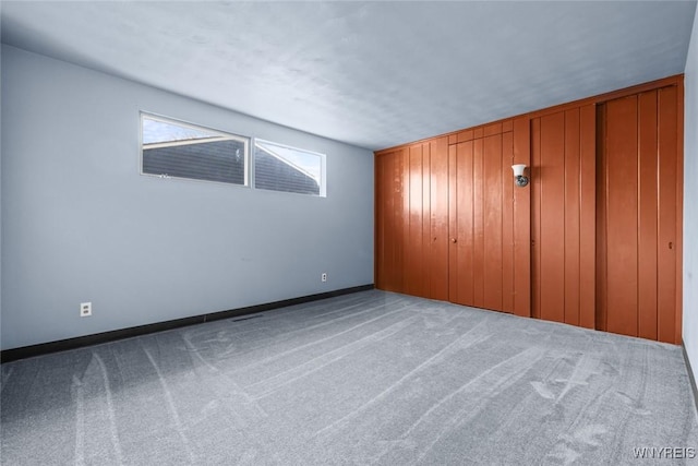 unfurnished bedroom with wood walls, carpet flooring, and baseboards