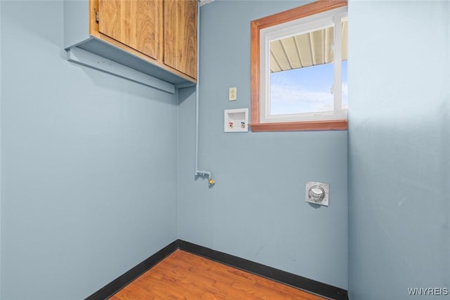 clothes washing area with wood finished floors, baseboards, hookup for a washing machine, and cabinet space