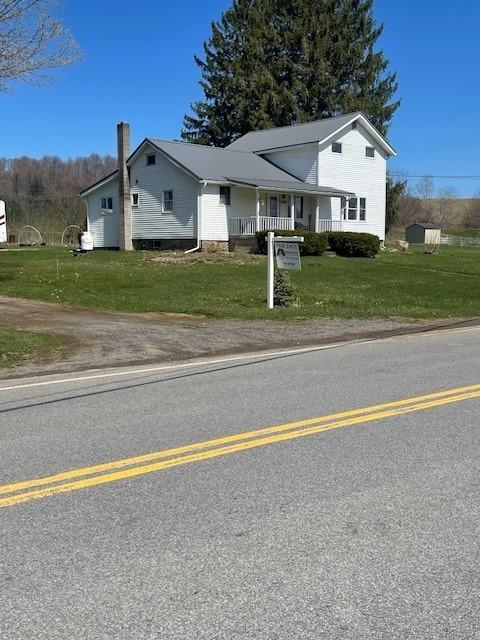 view of front of home featuring a front yard, covered porch, and a chimney