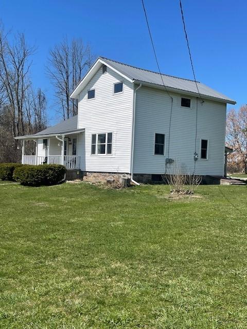 view of home's exterior featuring covered porch, metal roof, and a lawn