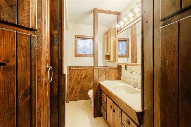 bathroom with toilet, a wainscoted wall, and vanity