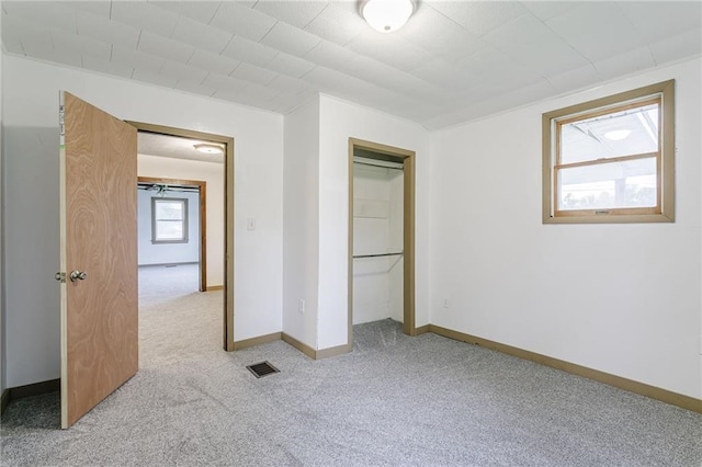 unfurnished bedroom with light colored carpet, visible vents, baseboards, and a closet